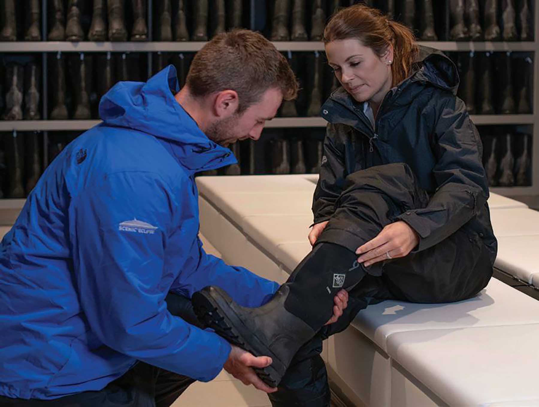A Scenic crew member helps a woman passenger fit her expedition boots