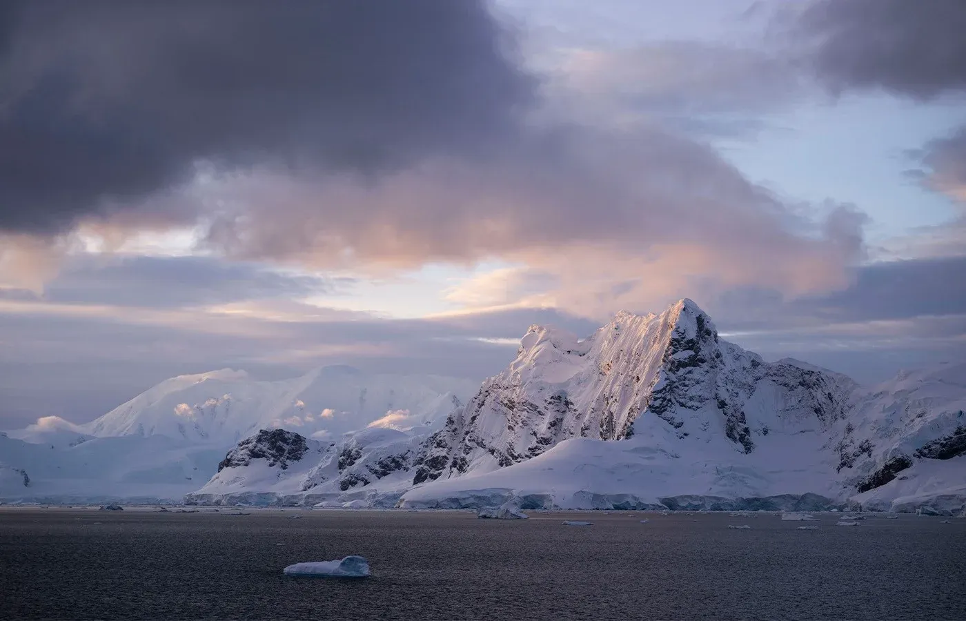 Sunset over snow-capped mountains along the Antarctic coast