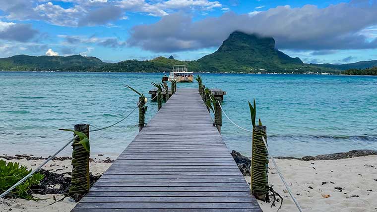 Small dock extending into a calm, crystal-clear Tahitian bay