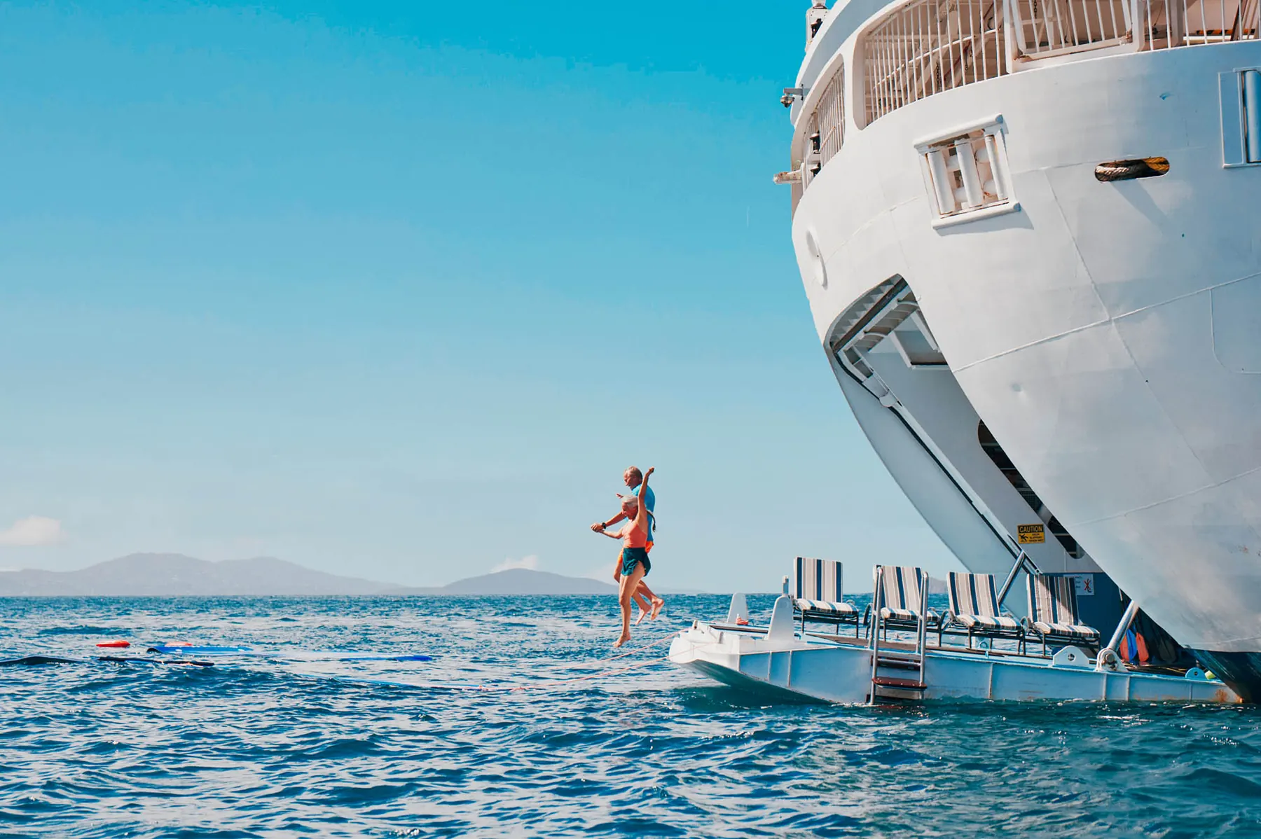 Guests jumping from Windstar Star Breeze's marina platform into turquoise water