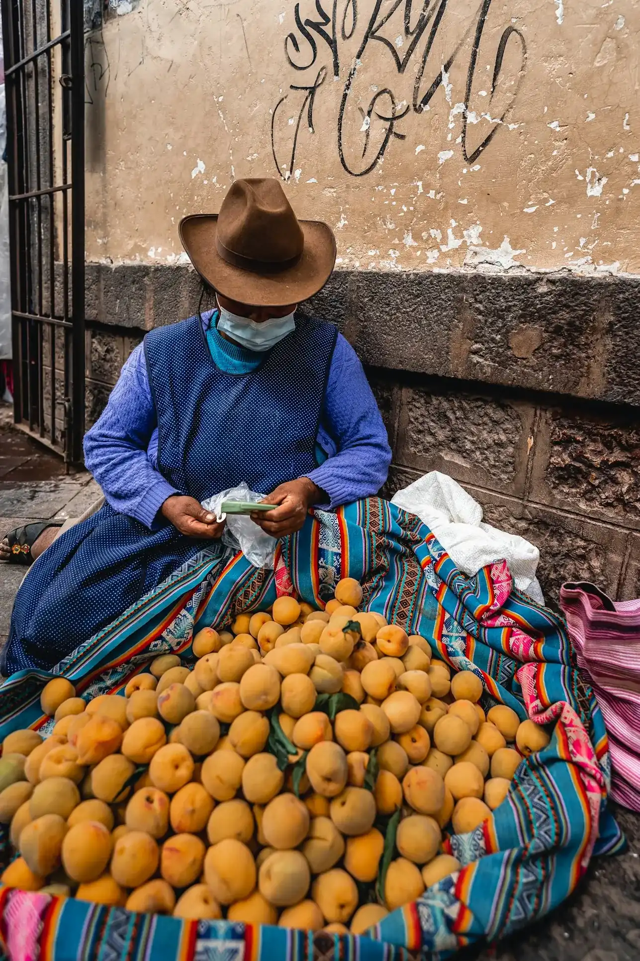 A vendor sits with a bag of fruit in a Peruvian village