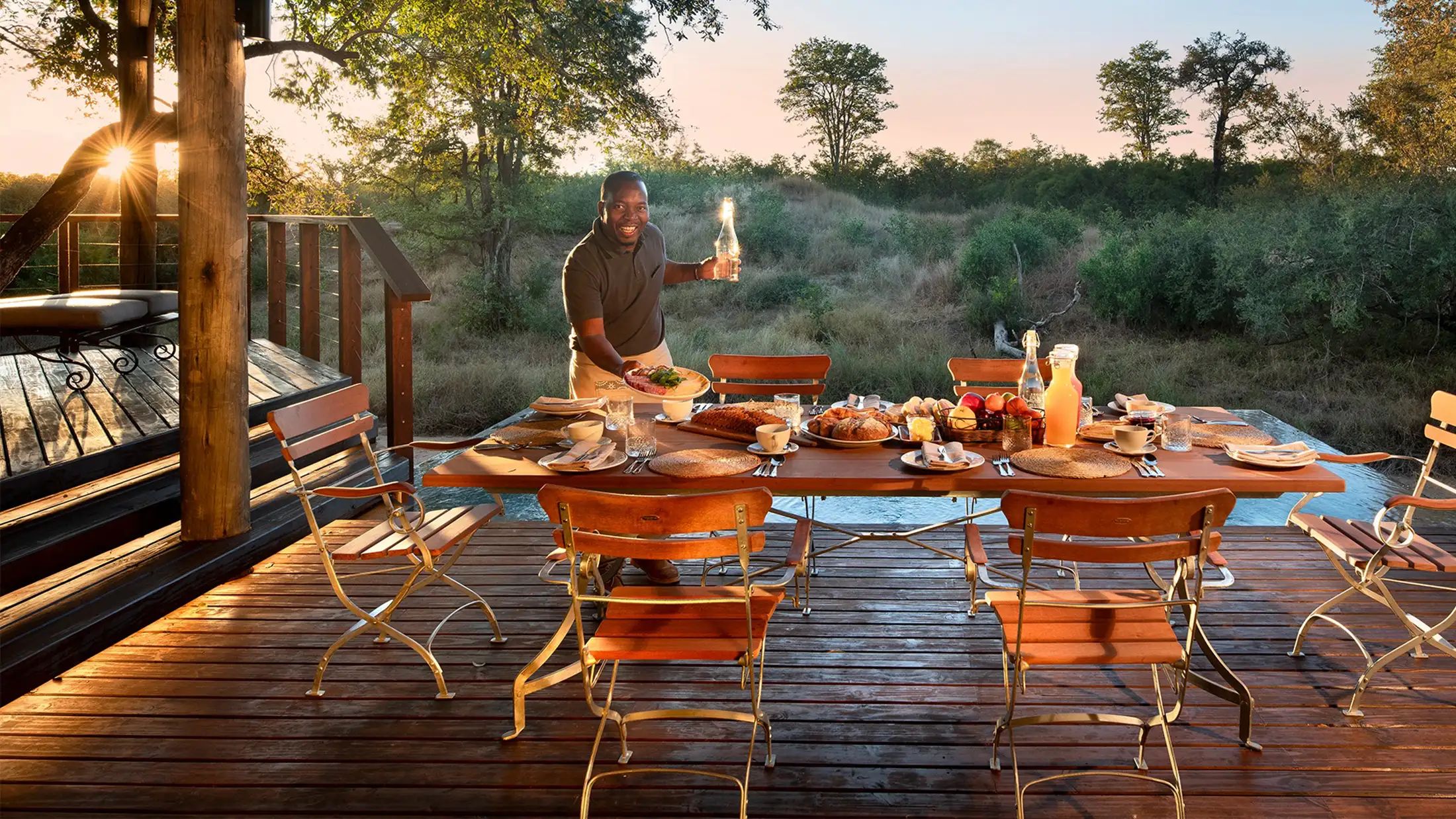 A server sets up dinner al fresco at &Beyond Ngala Safari Lodge