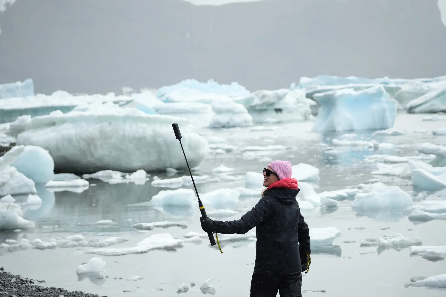A woman holds an action camera up in a snowy Antarctic scene