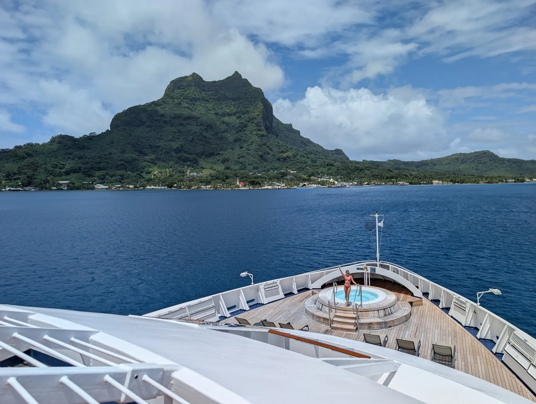 A woman waves from the bow hot tub on a cruise ship in Tahiti