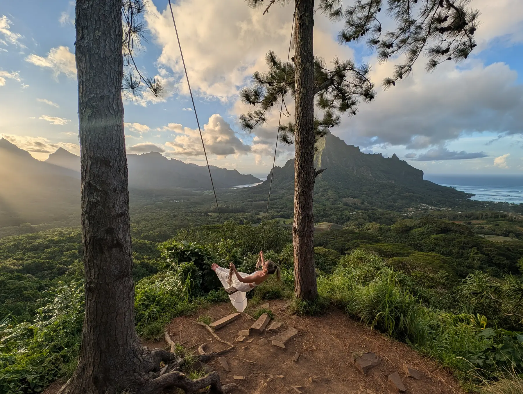 A woman swings in Tahiti at sunset