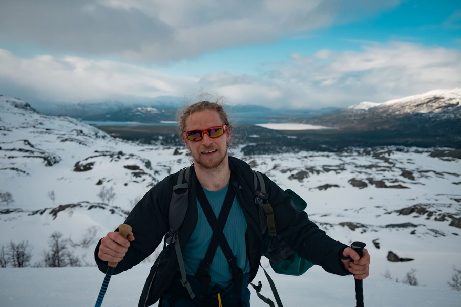 Hiker crossing a snowy ridge on a remote island in Arctic Norway