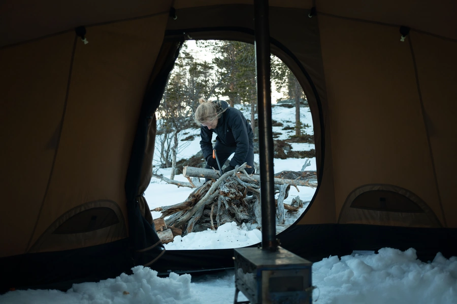 Cutting firewood beside the teepee camp during the Arctic land night