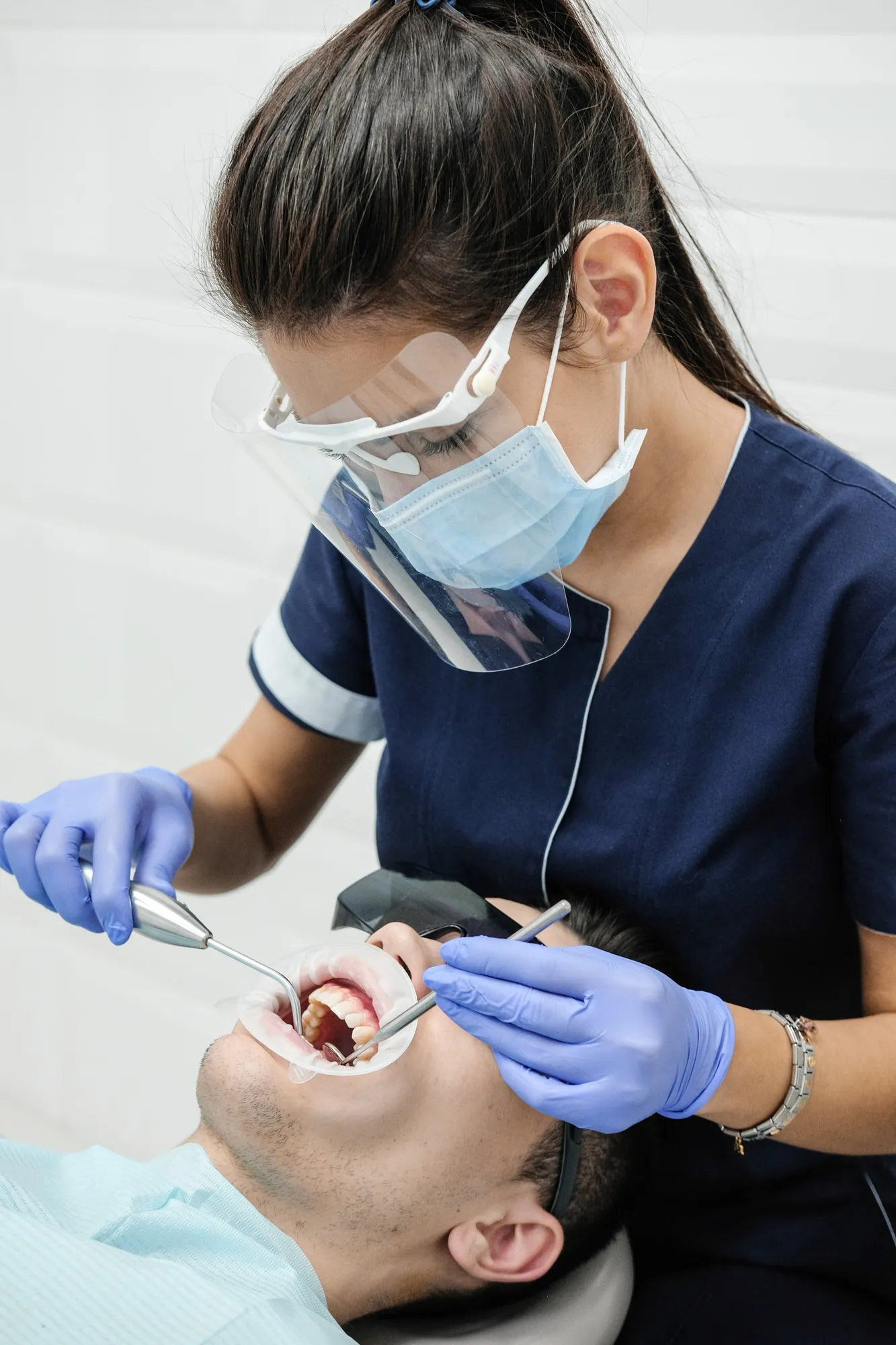 Dental professional performing a clinical procedure with protective equipment at Ava Dental.