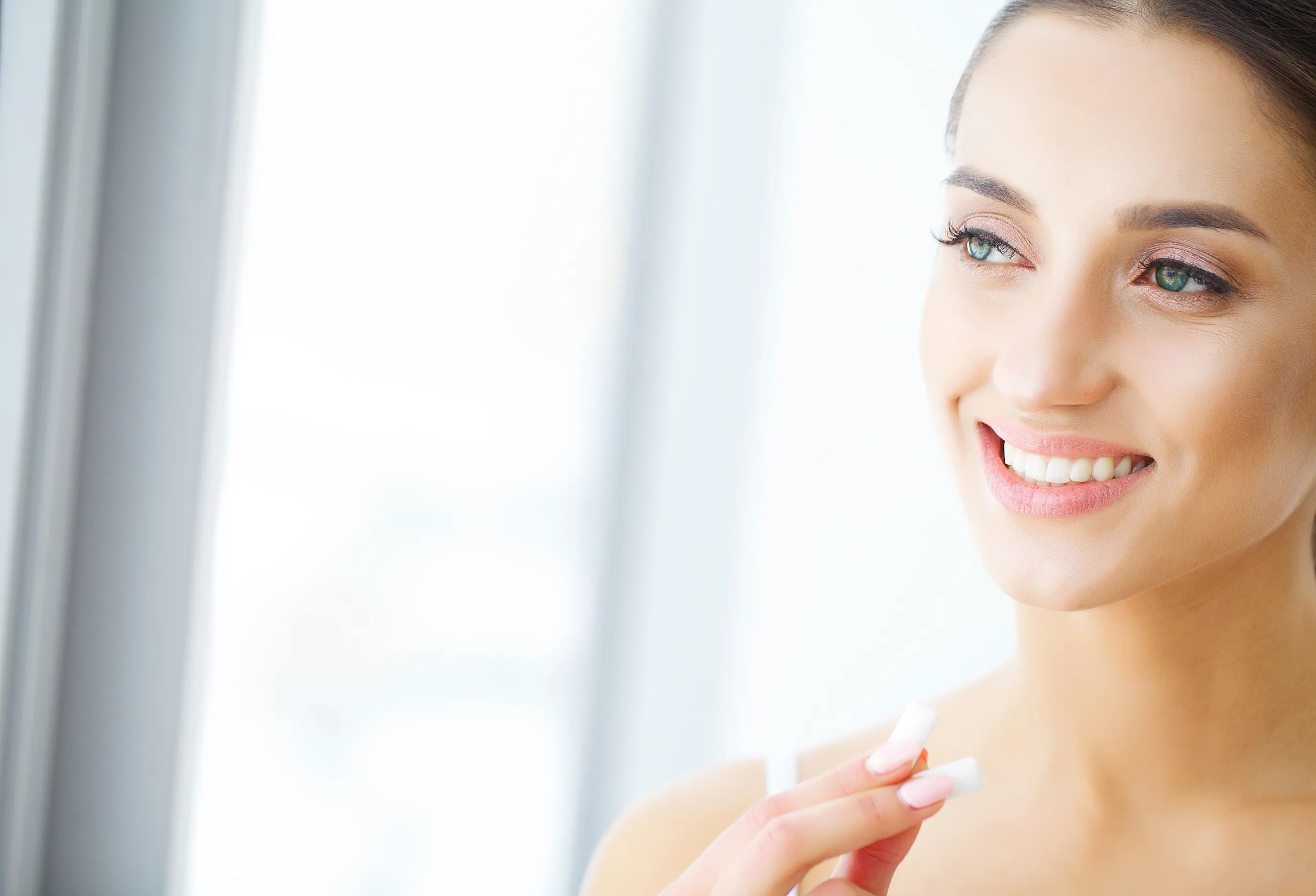 Patient smiling while holding a dental aligner, representing cosmetic dentistry at Ava Dental.