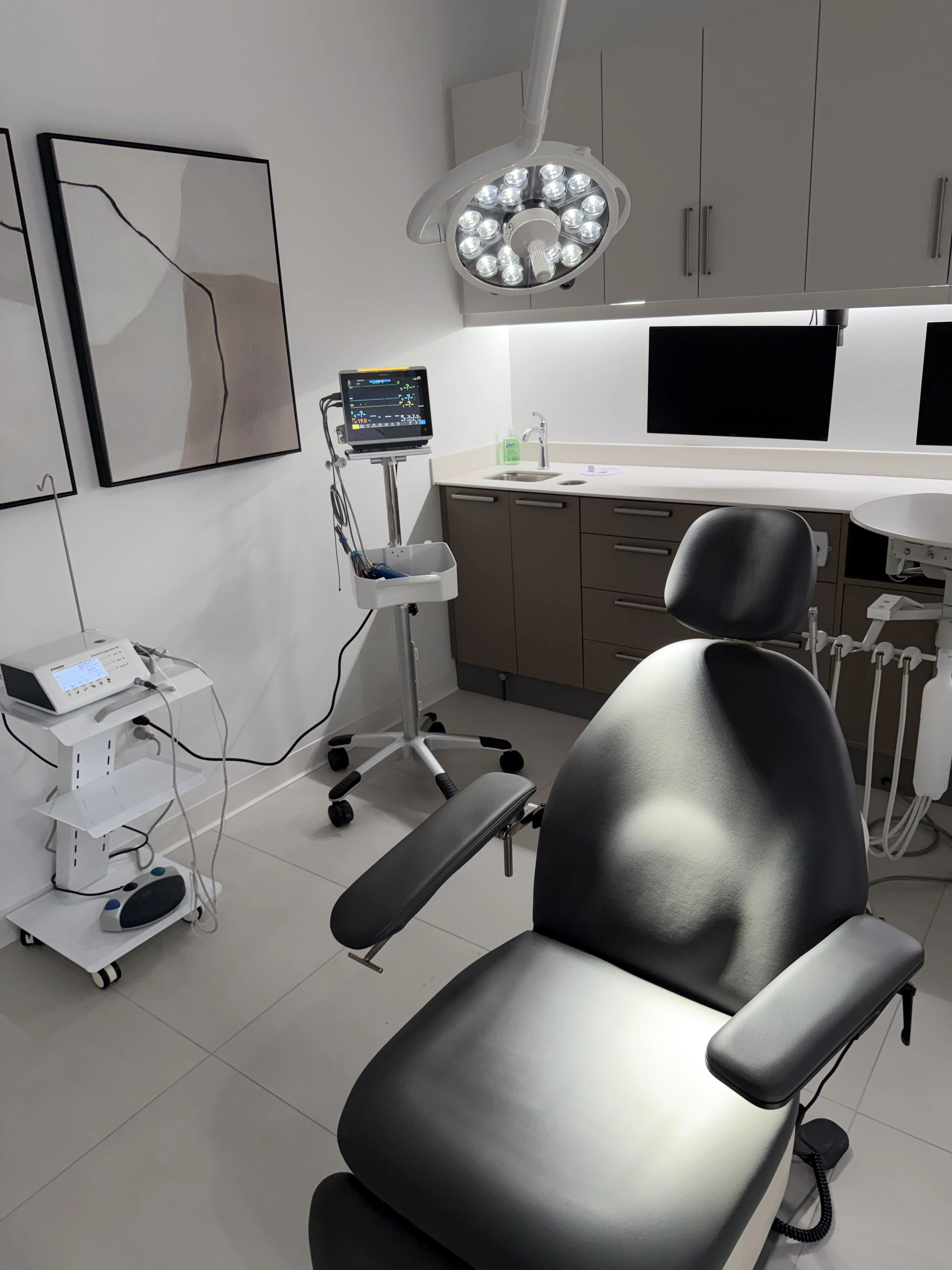 Dentist in white coat reviewing patient information with a woman sitting in a dental chair.