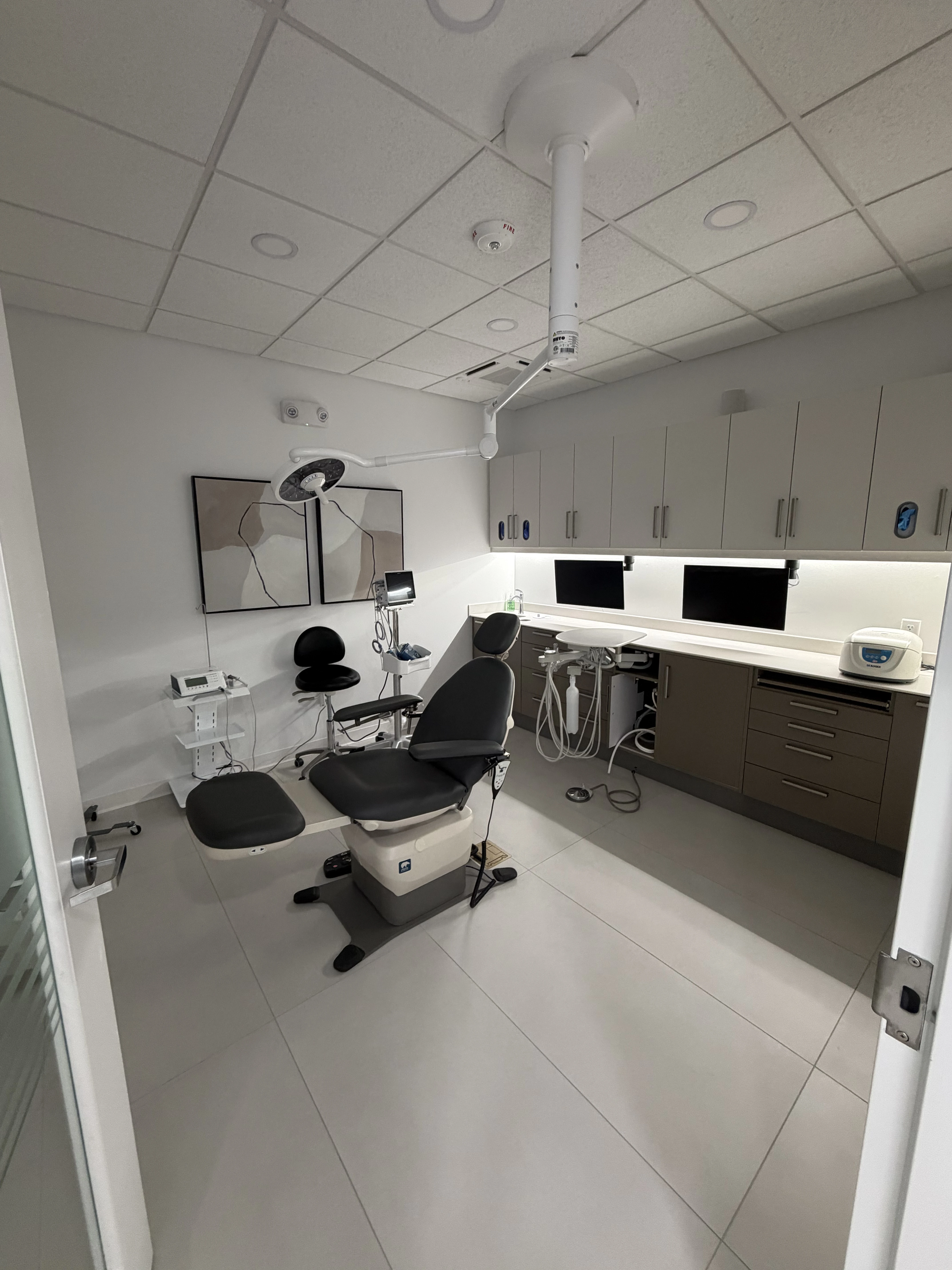 Dentist in white coat reviewing patient information with a woman sitting in a dental chair.