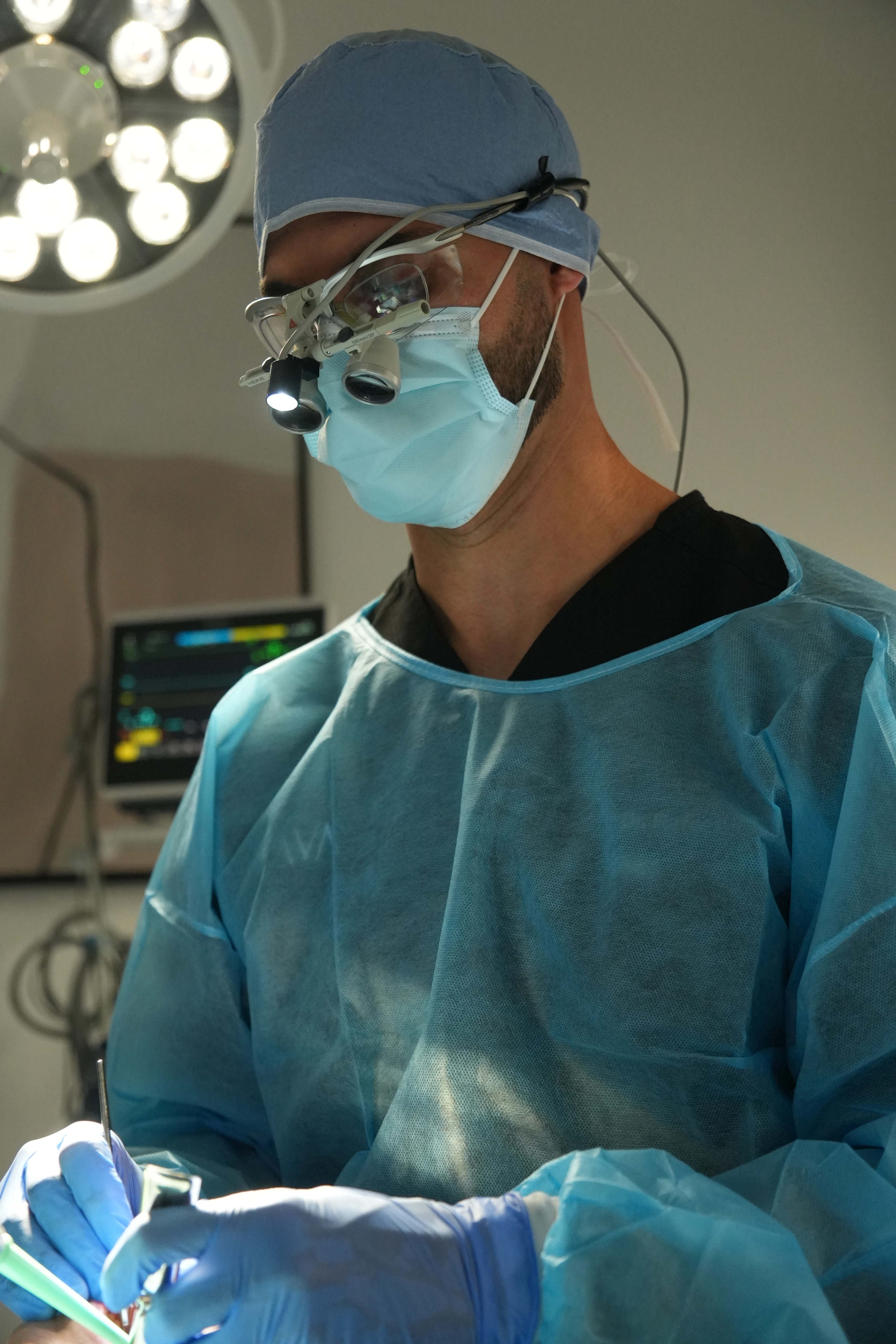 Dr. Rafik Dib wearing purple gloves examines a female patient's teeth using dental tools in a clinic.