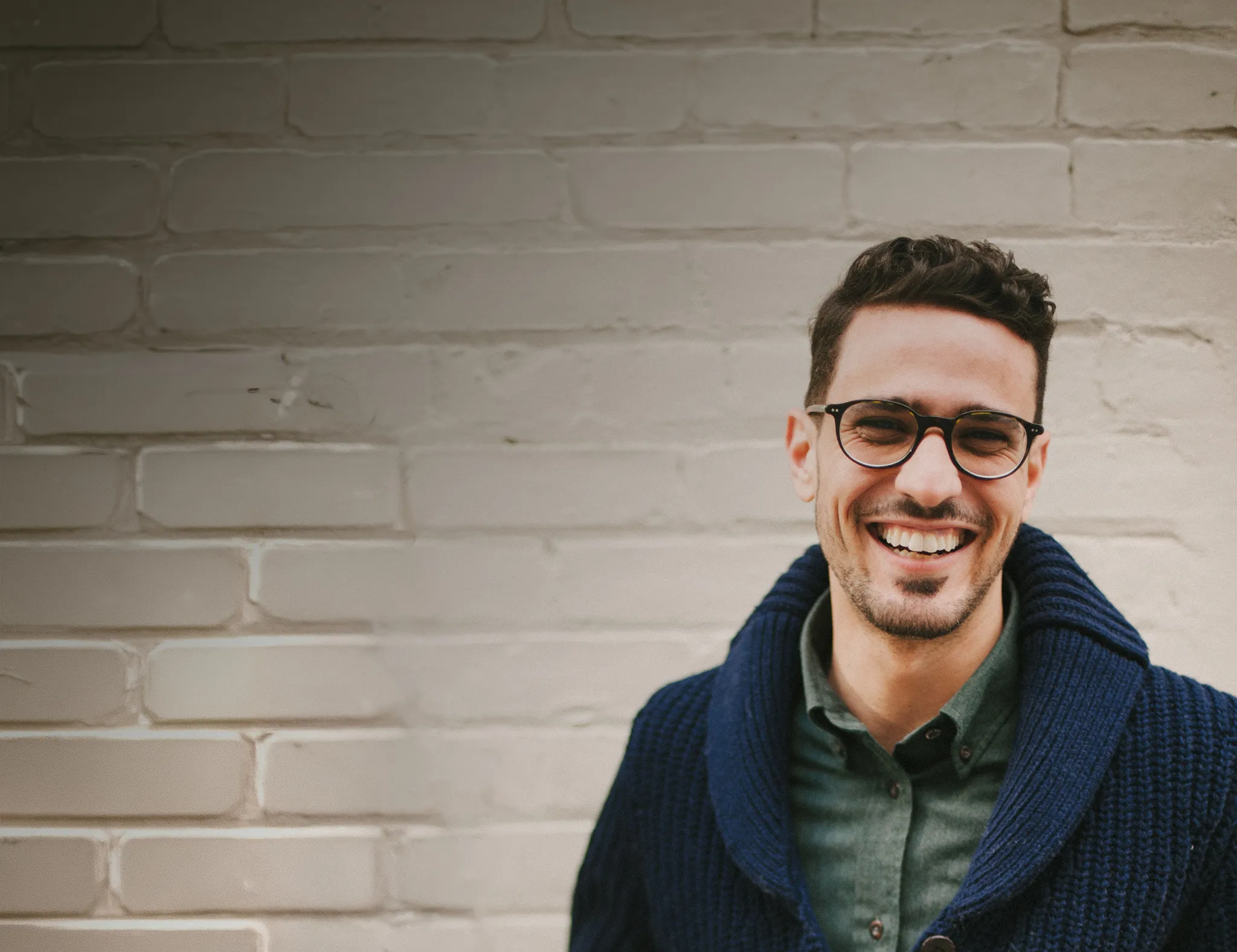Smiling man wearing glasses outdoors in front of a  building.
