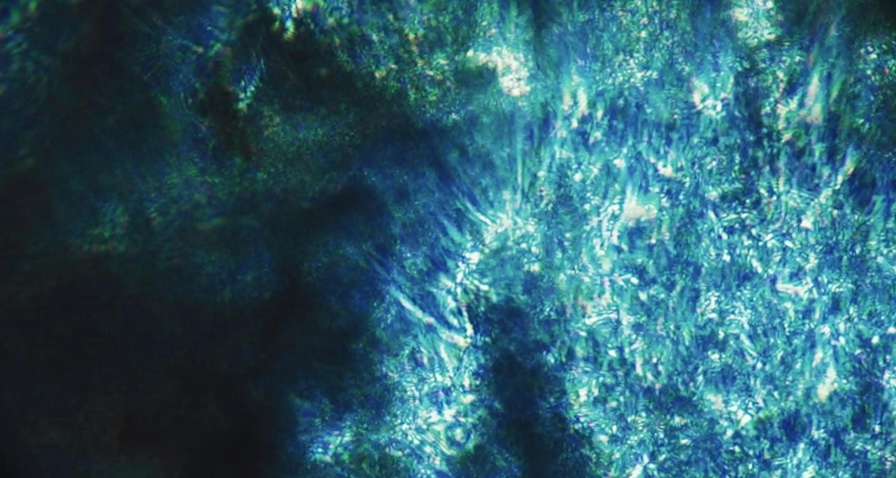 Close-up of blue and green textured abstract pattern with light reflections.