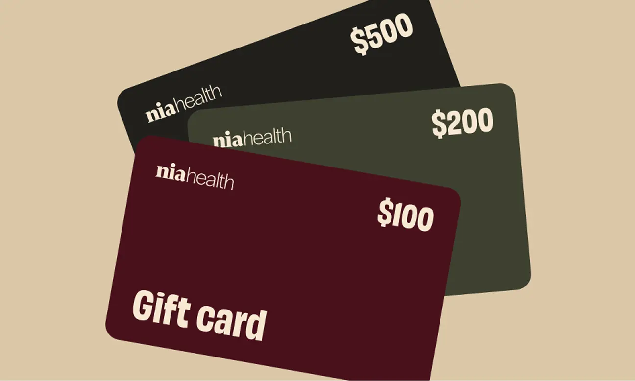 Three niahealth gift cards stacked, showing values of $100, $200, and $500 on a beige background.