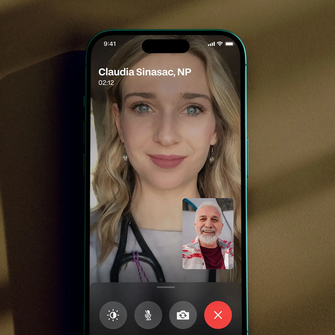 Video call on smartphone showing a female healthcare provider labeled Claudia Sinasac, NP, and a smiling older man in a small inset window.