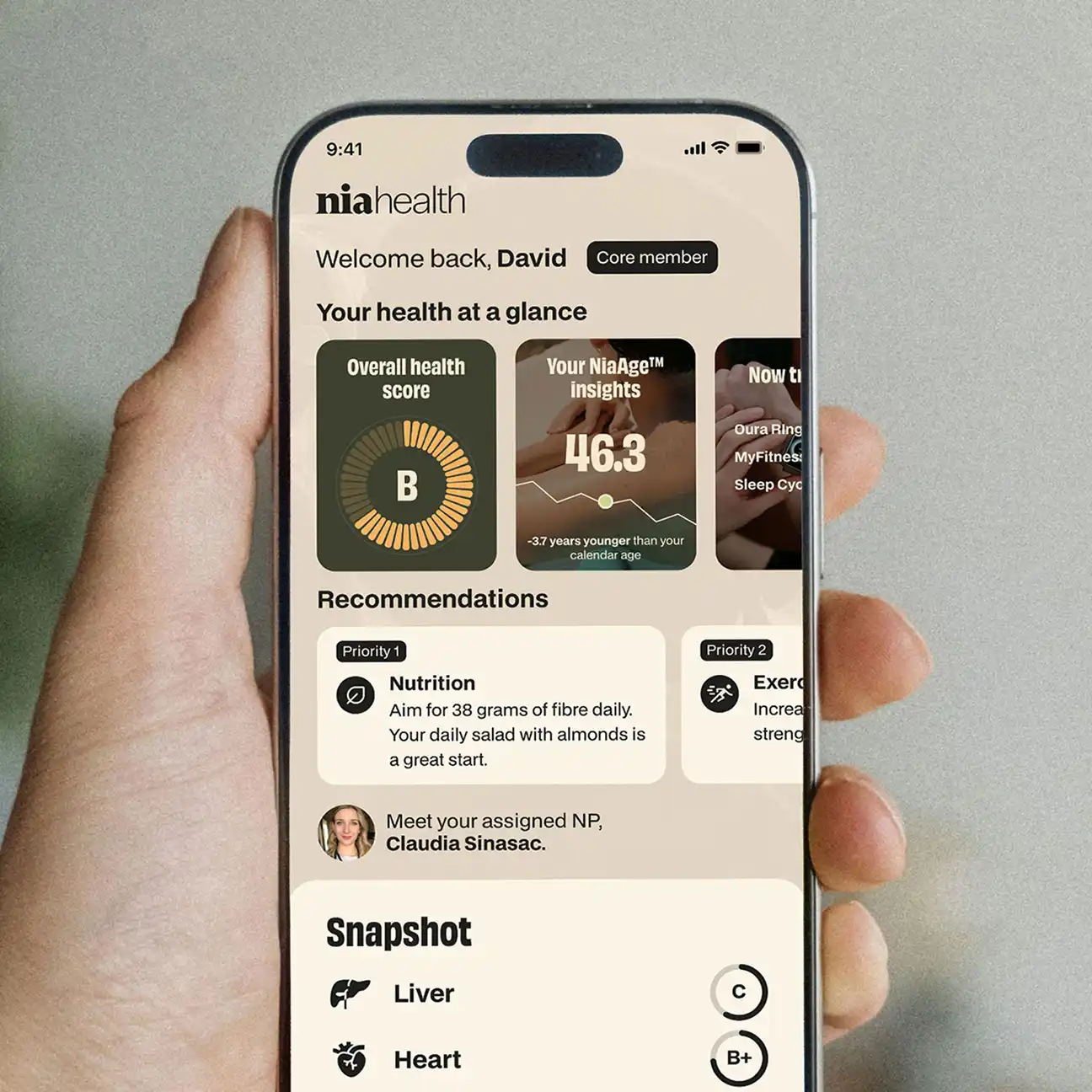 Hand holding smartphone displaying niahealth app with overall health score B, NiaAge insights 46.3, nutrition recommendation to aim for 38 grams of fiber daily, and snapshot scores for liver and heart.