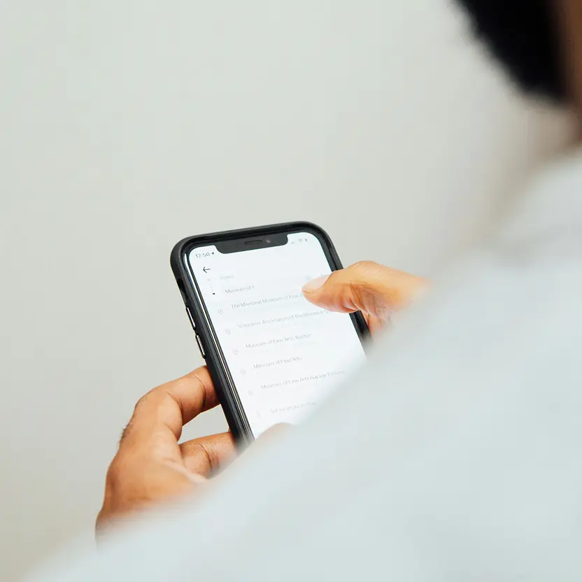 Person using a smartphone with a list of location names displayed on the screen.