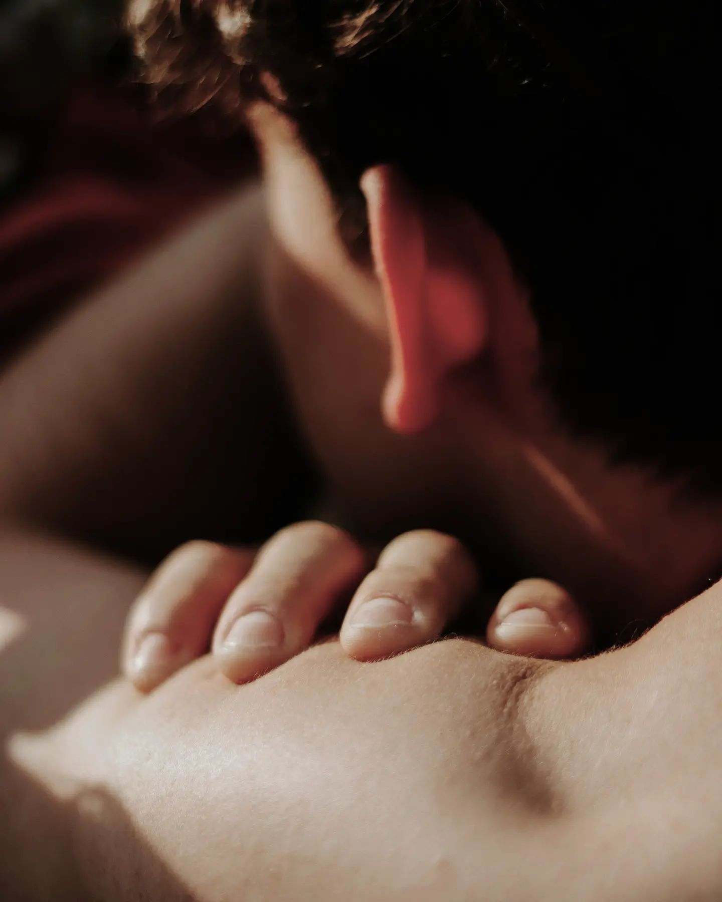 Close-up of a person’s hand resting on their shoulder with the back of their head visible.