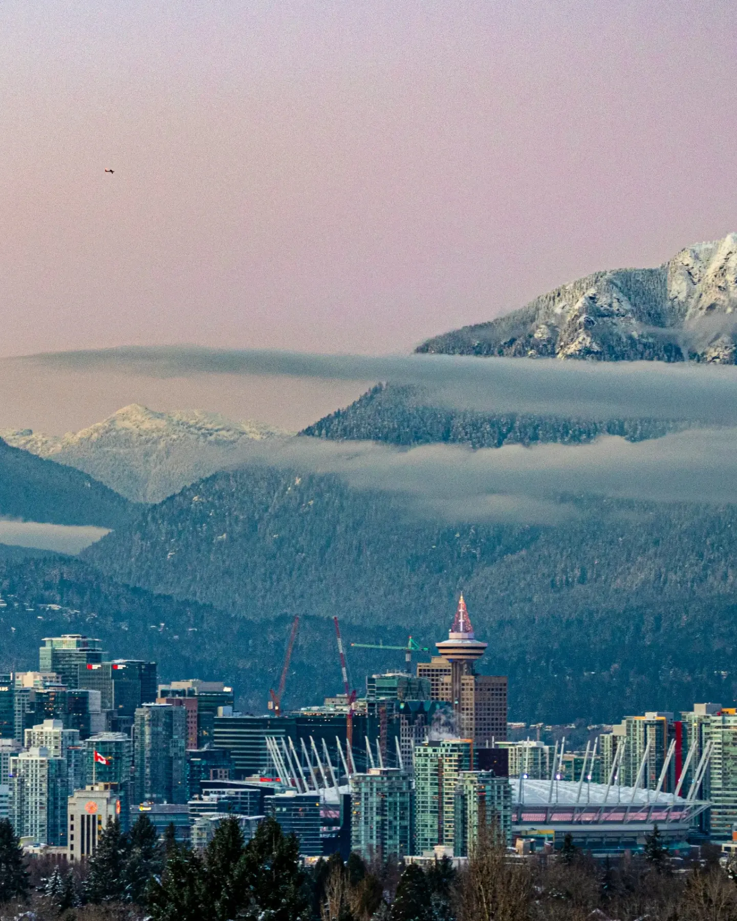 Downtown Vancouver below snow-capped North Shore mountains at dusk