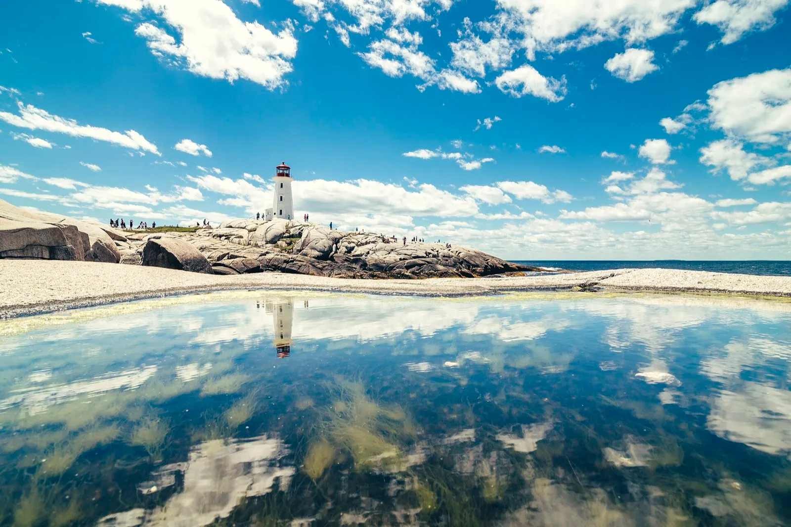 Peggy's Cove lighthouse on granite rocks in Nova Scotia, reflected in a tide pool