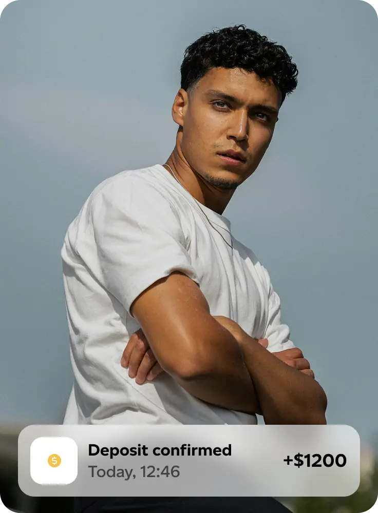 Man in white t-shirt with arms crossed looking to the side with a notification overlay showing deposit confirmed of $1200.
