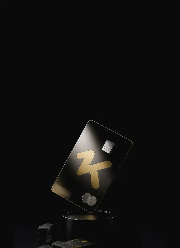 Black credit card with golden logo and chip, displayed upright on a black pedestal against a dark background.