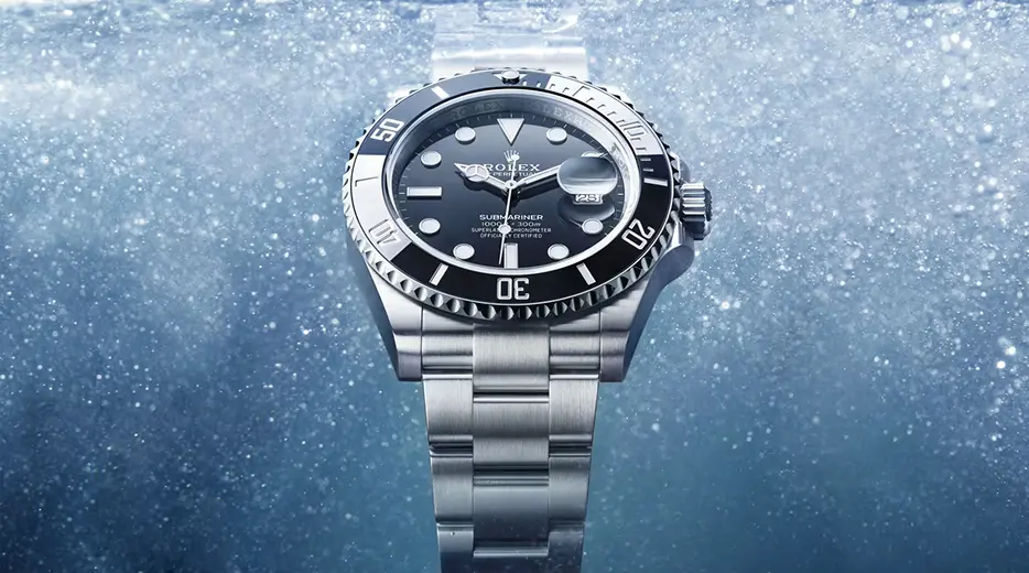 Rolex Submariner wristwatch with black dial and stainless steel band underwater with bubbles.