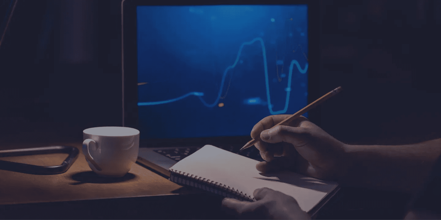 Person taking notes before stock chart - Best Prop Firms in Uganda