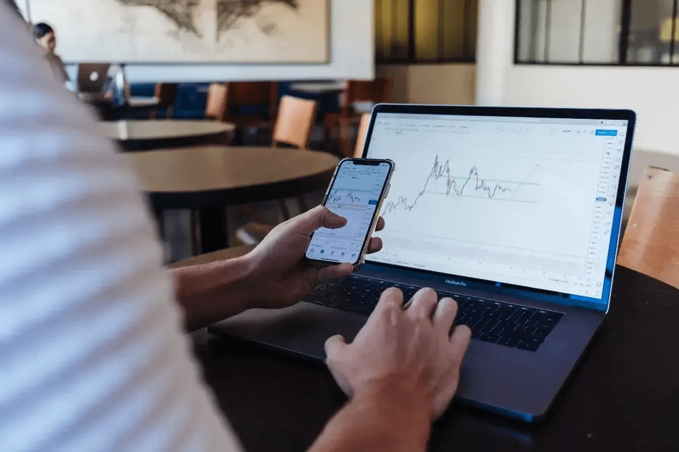Person analyzing financial charts on devices - Best Prop Firms in Uganda