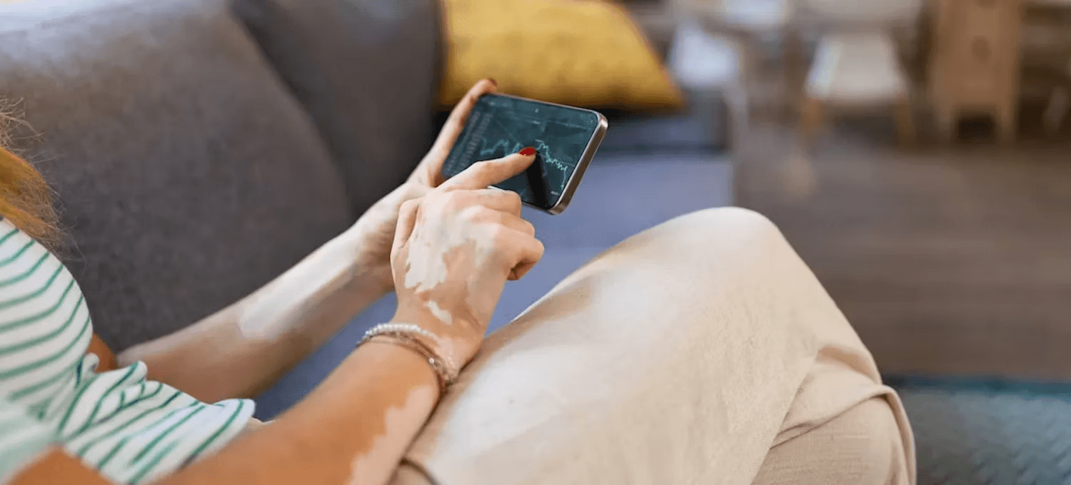 Person checking stock charts on phone - Paper Trading For Beginners