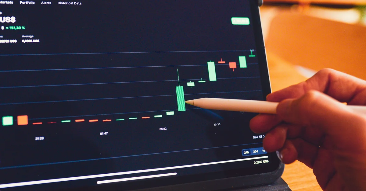 Tablet showing candlestick trading chart with stylus pointing at green candle — how to become a prop trader