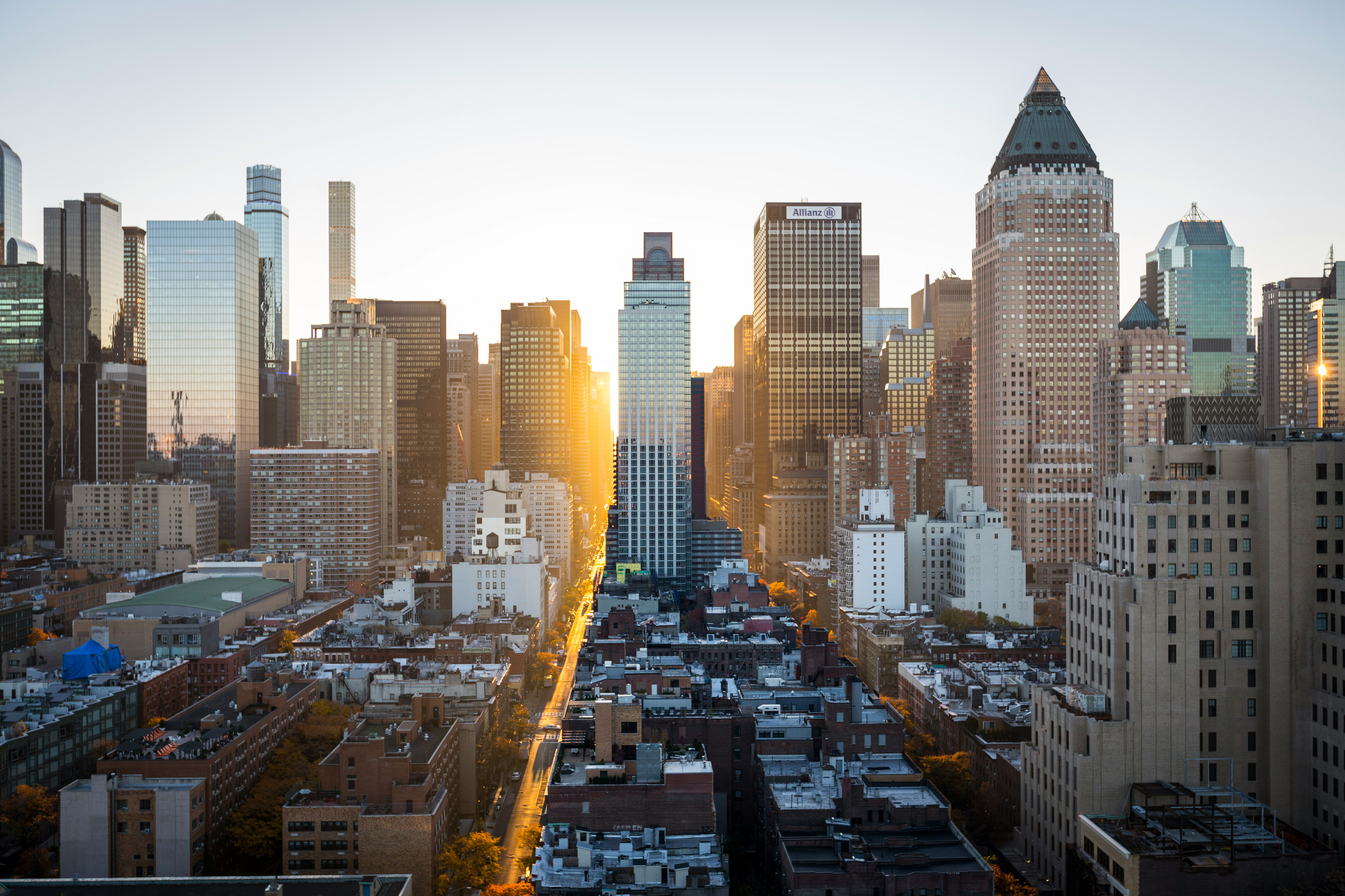 Sunlight shining between tall skyscrapers in a city skyline at sunset.