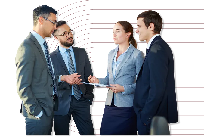Four business professionals in suits engaged in a discussion with one woman holding a clipboard.
