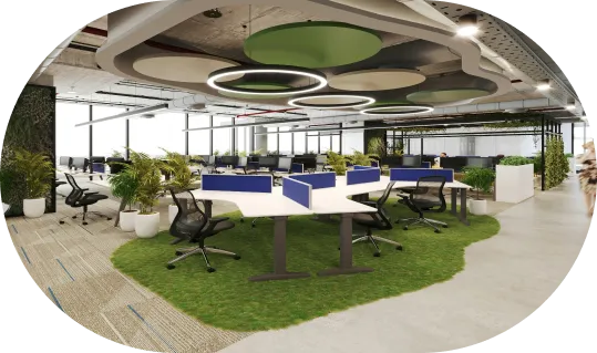 Modern open office with green carpet, white desks, blue dividers, black chairs, hanging circular lights, and indoor plants.