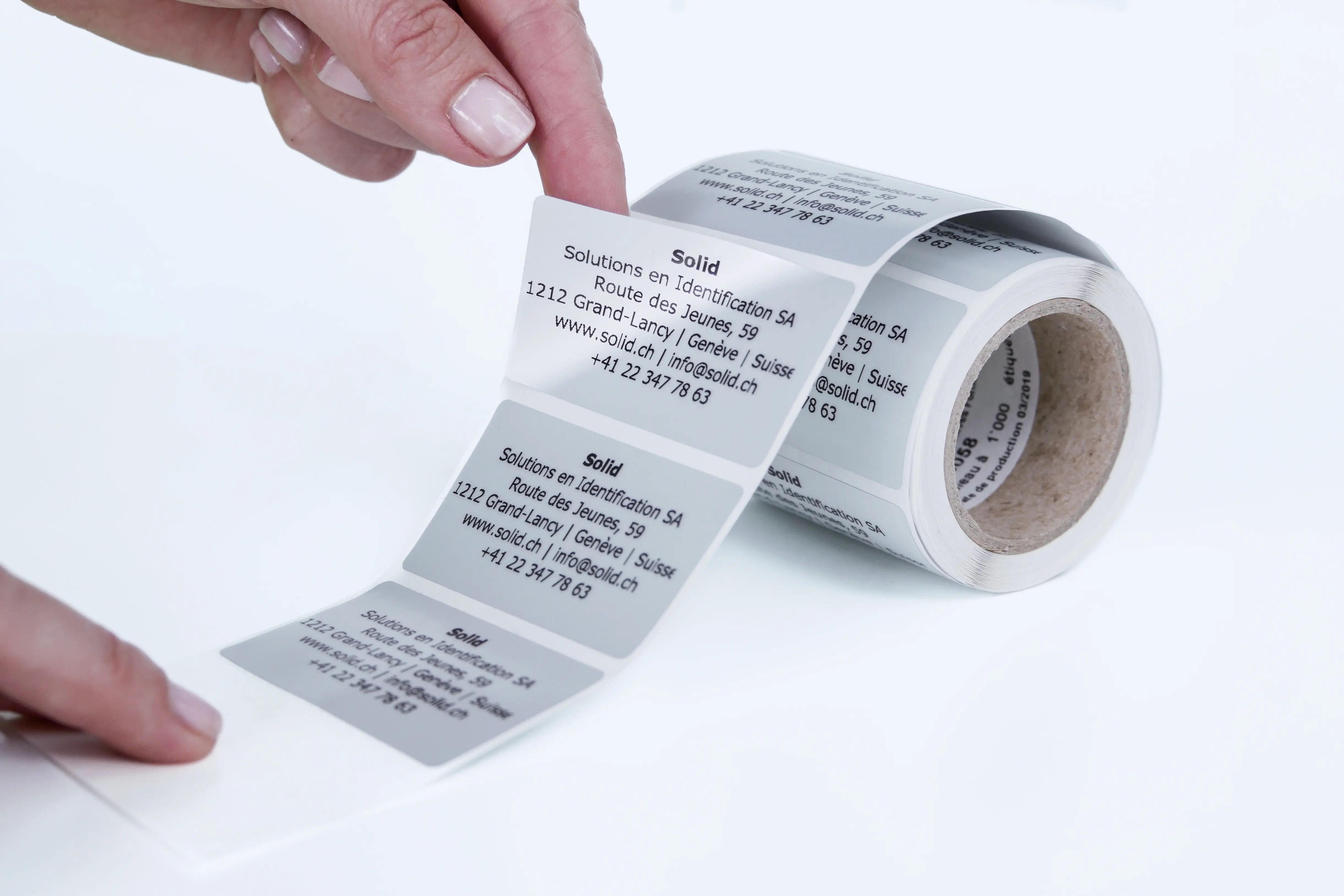 Hand removing an adhesive label from a roll