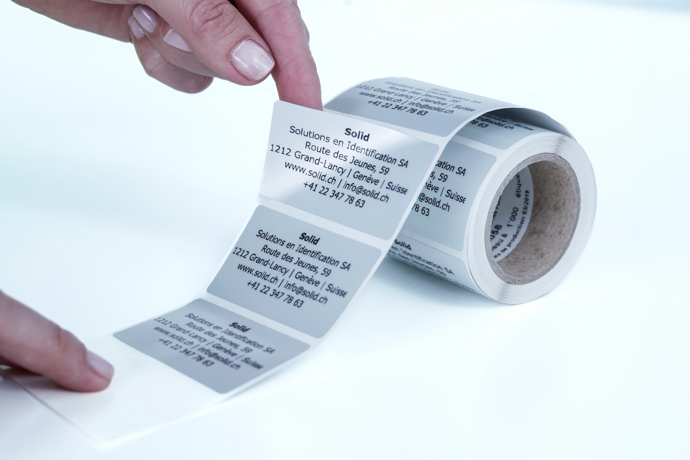 Mano che stacca un'etichetta adesiva da un rotolo