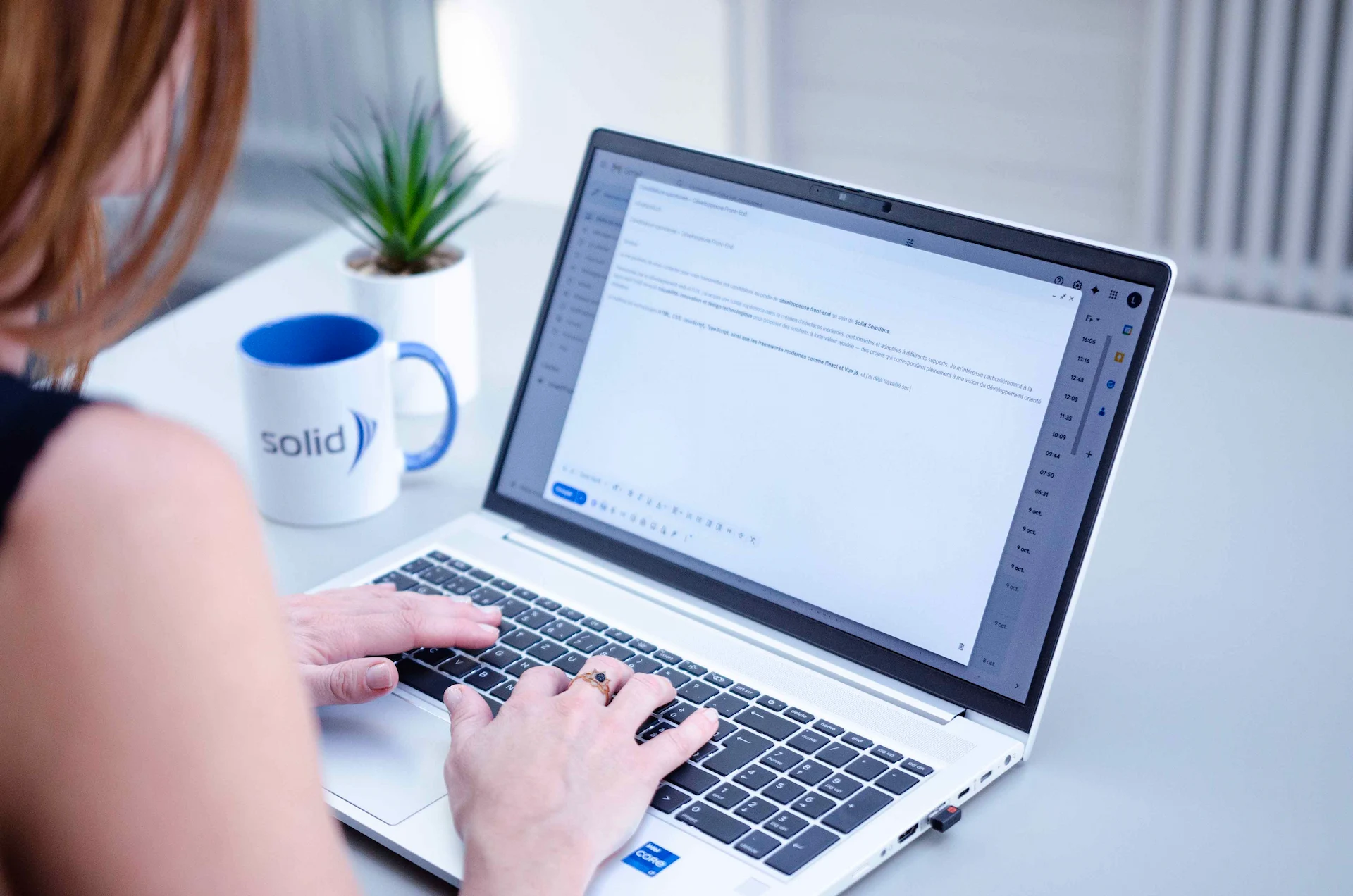 Donna vista di spalle mentre scrive un'e-mail di lavoro sul suo computer