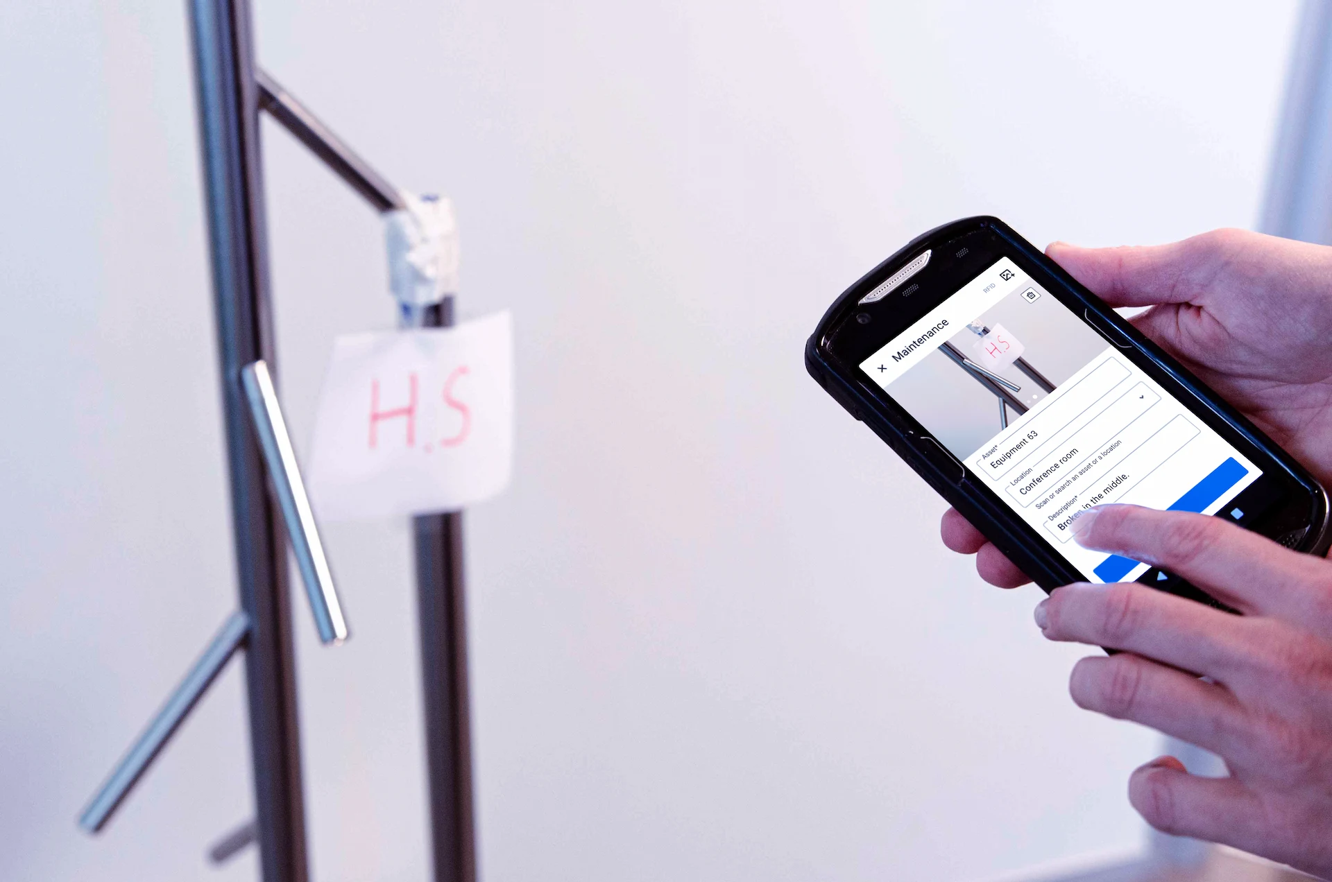 Smartphone che mostra una schermata di manutenzione di un oggetto, un oggetto fuori servizio sullo sfondo