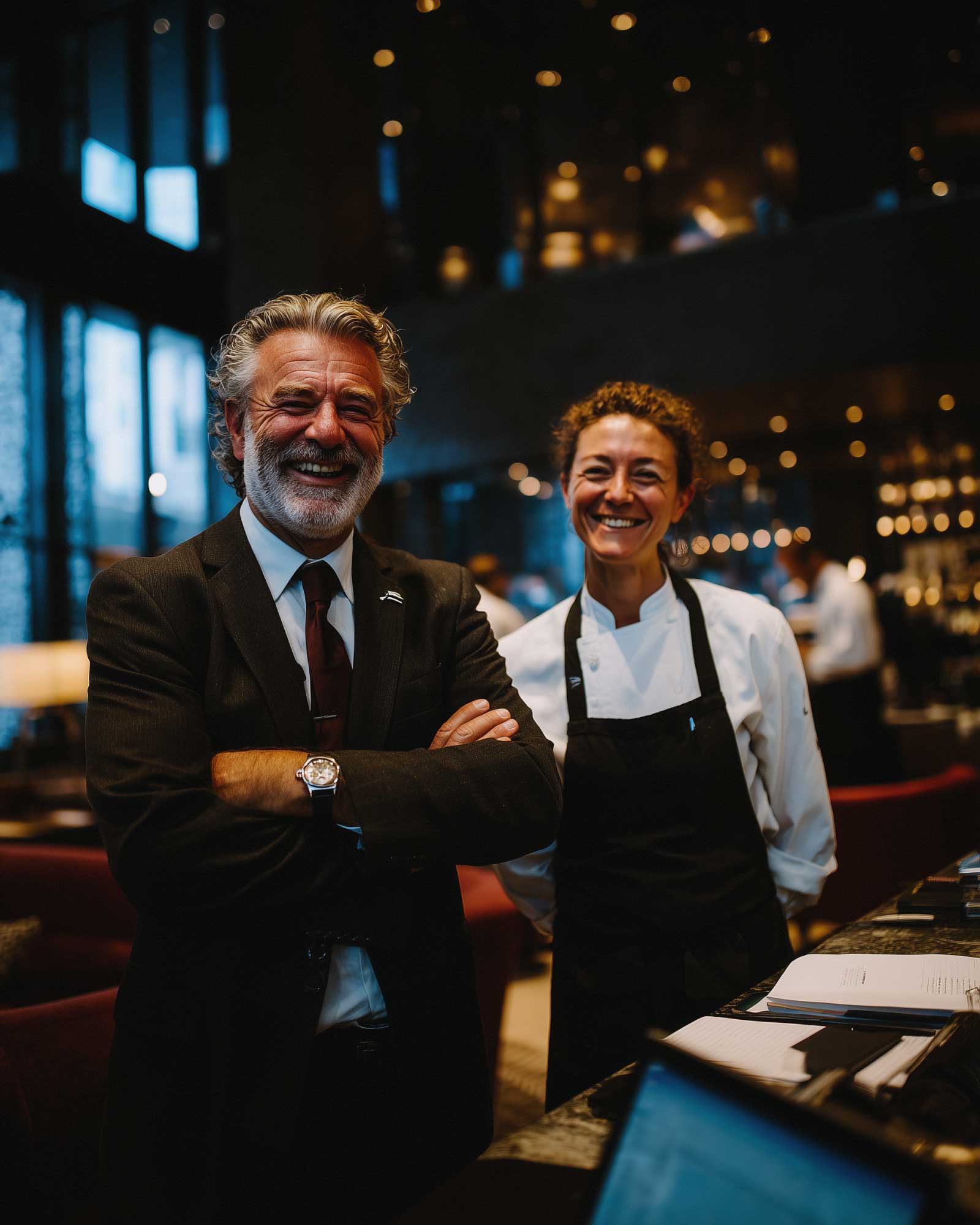 Restaurant manager and chef smiling and standing together in an upscale dining space
