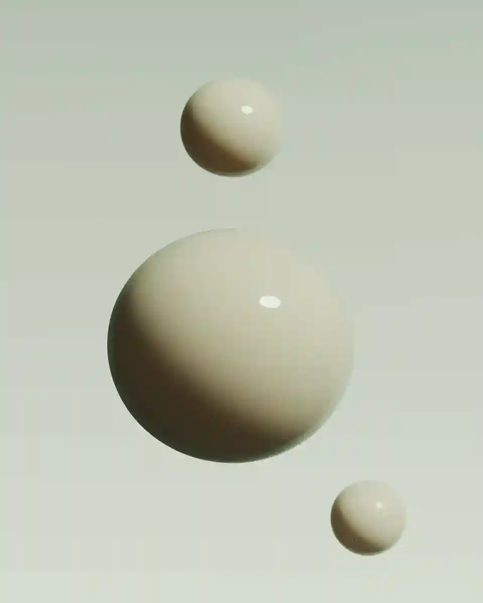 Three beige spheres of different sizes floating on a light gray background with subtle shadows and highlights.