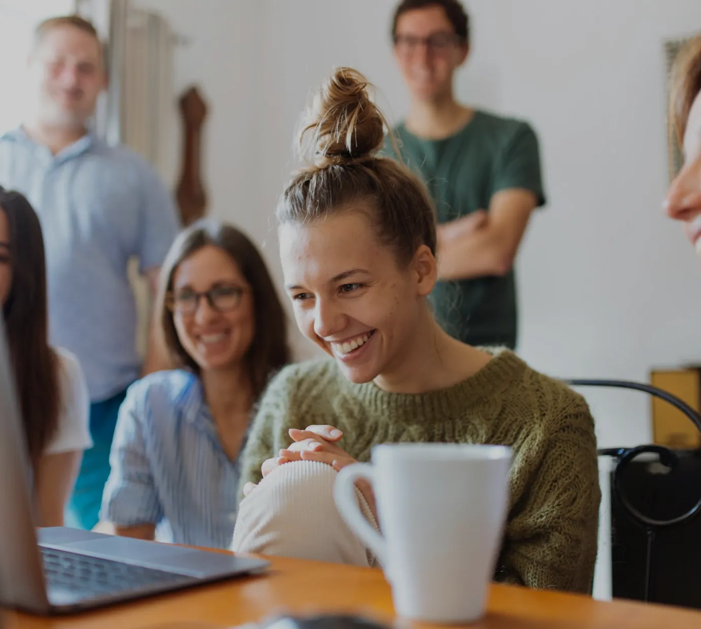 Group smiling while watching something on a laptop