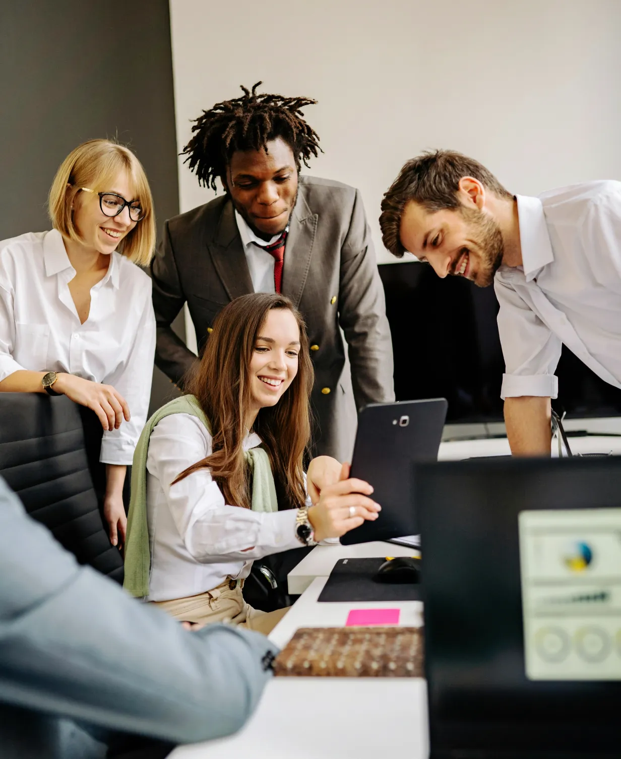 A woman with curly hair and a blue headband sits at a table, holding a pen and looking off-camera.