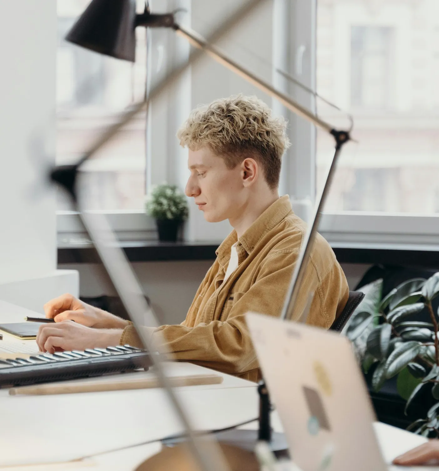 A person with curly hair and a blue headband sits at a table, holding a pen and looking off-camera.