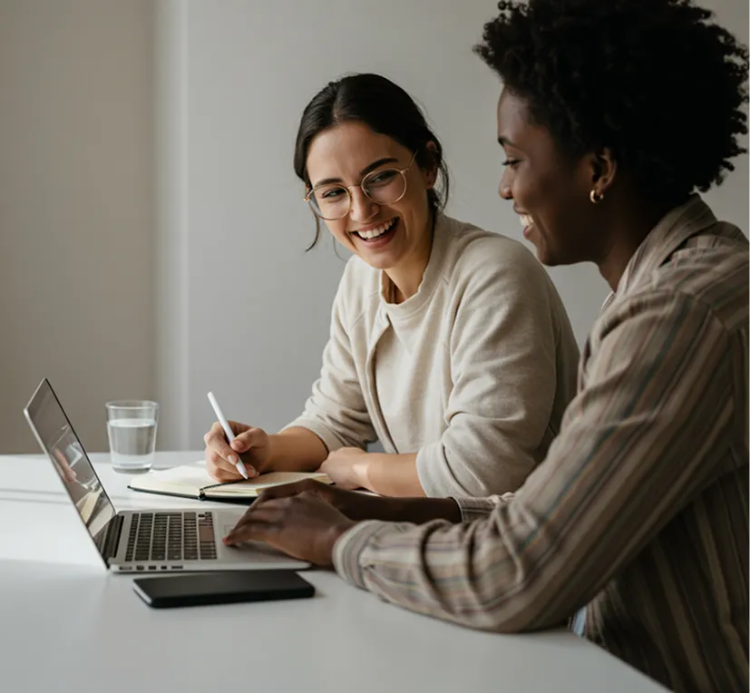 Two colleagues collaborating and smiling at a laptop