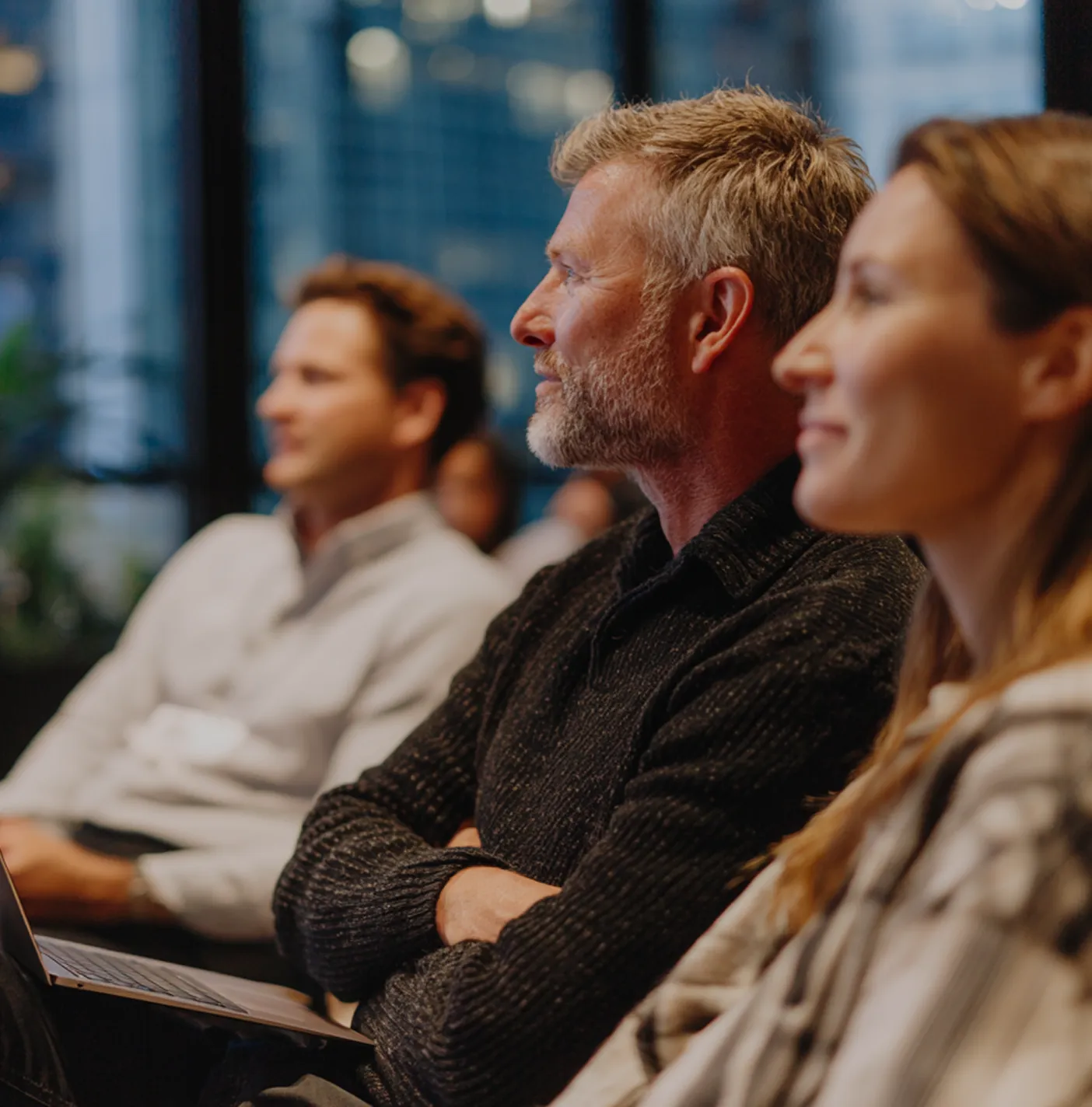 A profile of a middle-aged man with graying hair sitting in an audience.