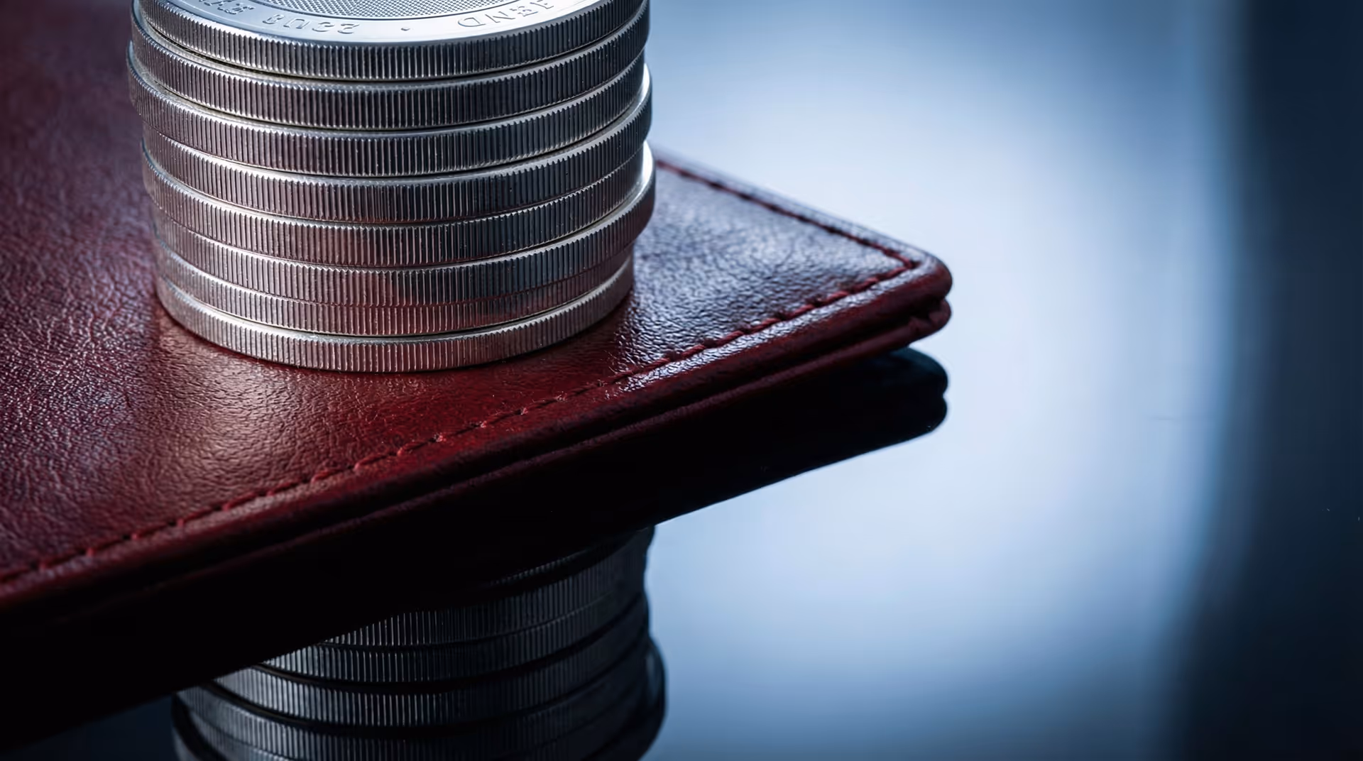 Detail sloupečku mincí a kožené peněženky.