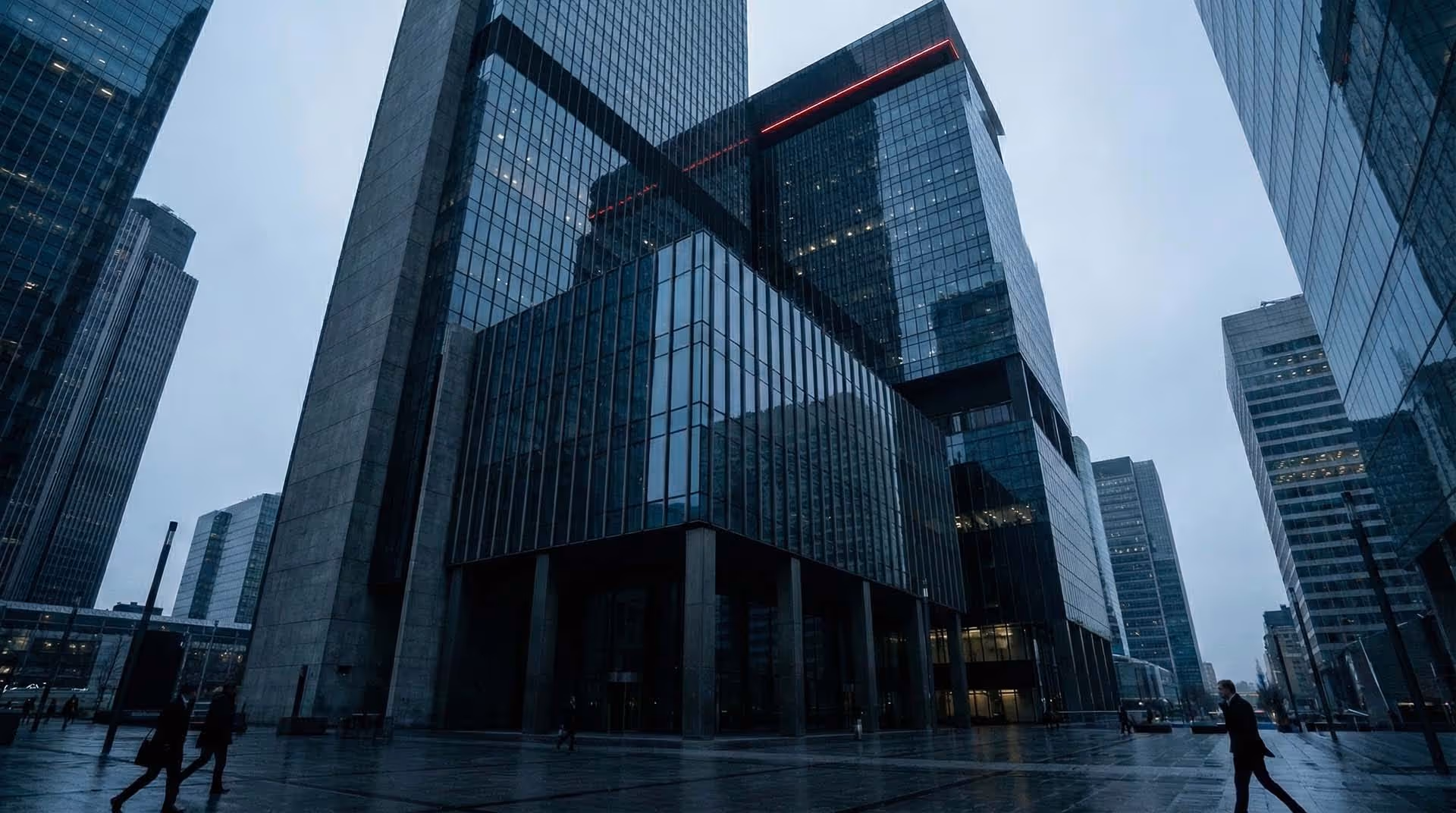 Pohled zdola nahoru na prosklenou fasádu moderního mrakodrapu.