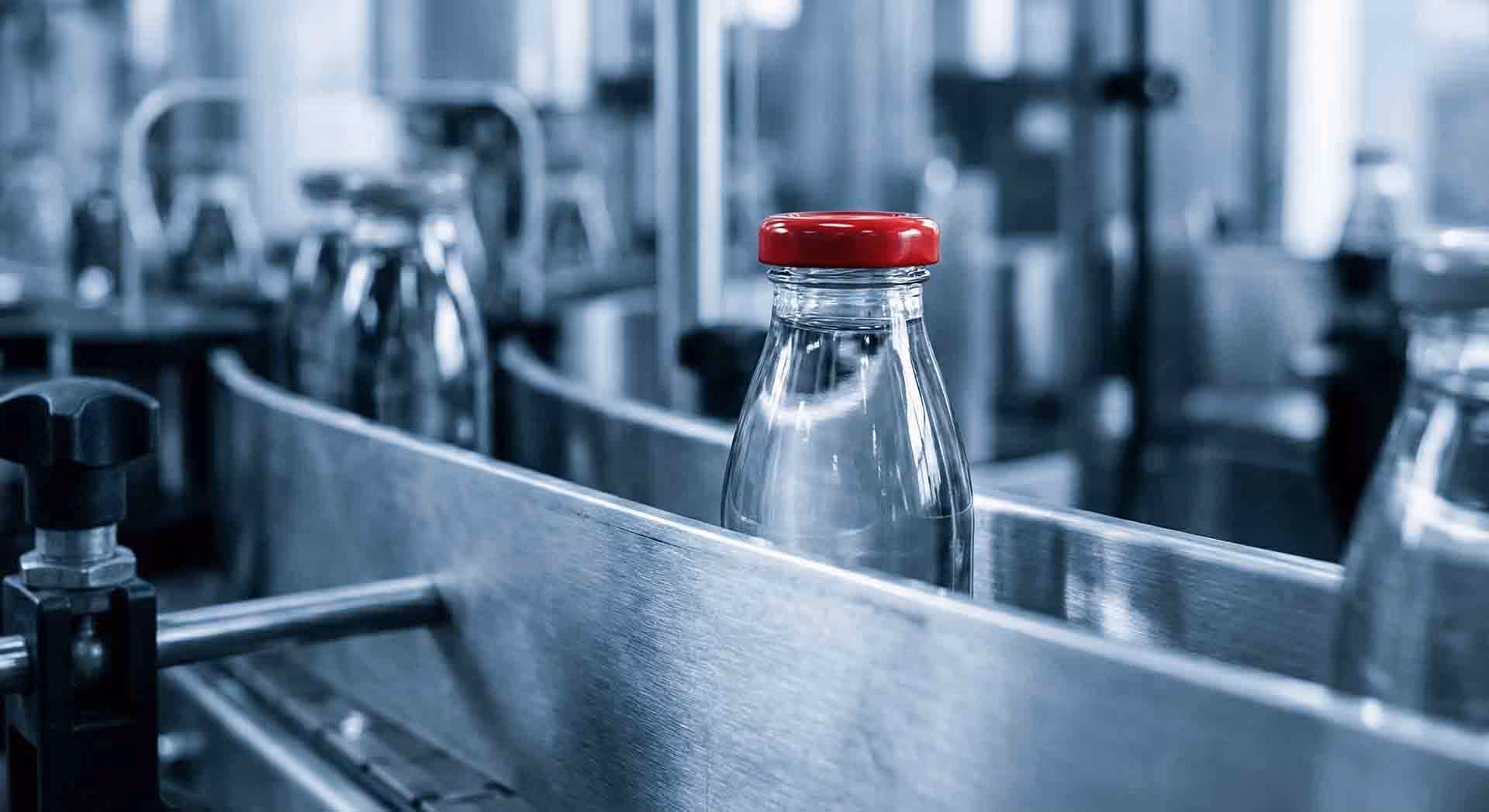 Skleněné lahve jedoucí na výrobním pásu.