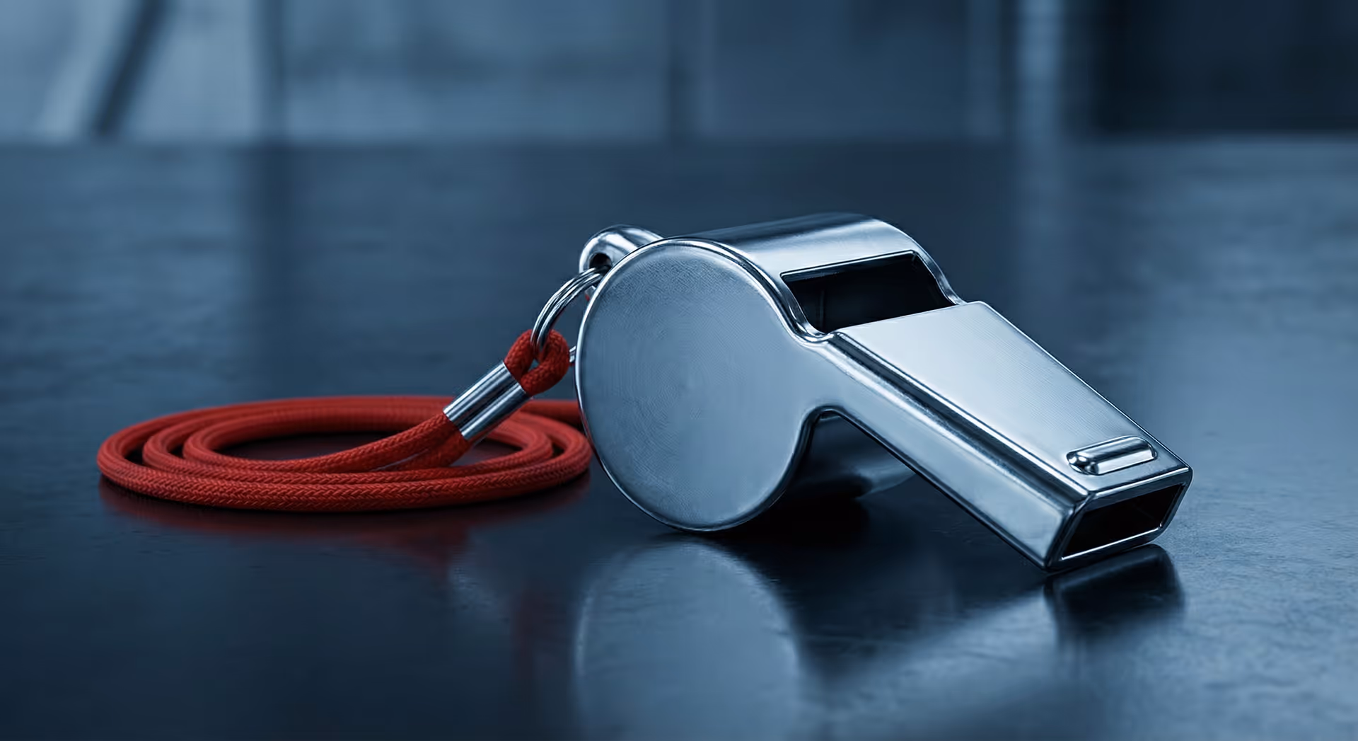 Kovová píšťalka na červené šňůrce.